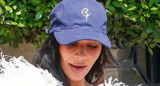 Kim Kardashian teams her feathered gown with a baseball cap