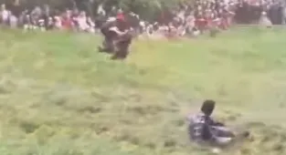 Moment man somersaults down huge hill during cheese-rolling race
